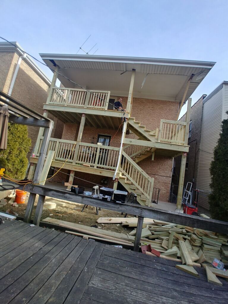 Backyard wooden deck construction with stairs and materials.