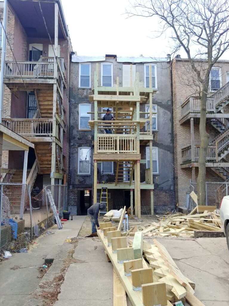 Construction workers building a new wooden staircase on the exterior of a multistory residential building.