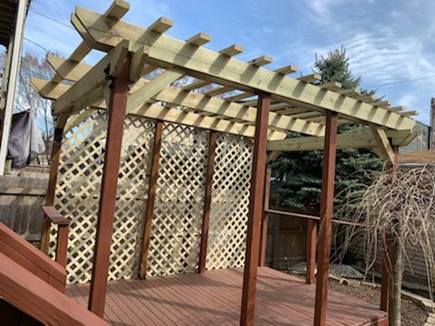 Wooden deck with a pergolas and lattice privacy screens in a residential backyard. Cost To Build A Pergola