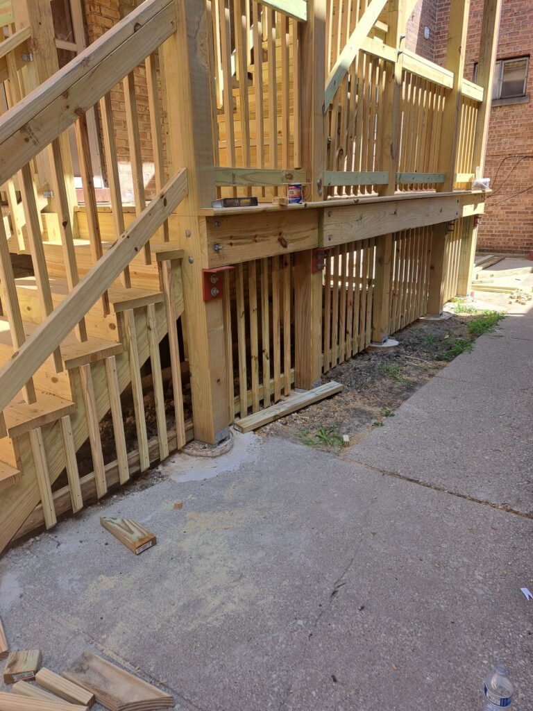 Wooden gate and balustrade of an outdoor deck in construction with tools and materials scattered around.