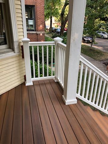 Corner view of a porch with Trex decking, white balustrade, and a cream-colored house exterior.