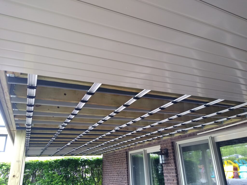 Underside view of a beige house's overhang with exposed wooden Beam and diagonal metal bracing.