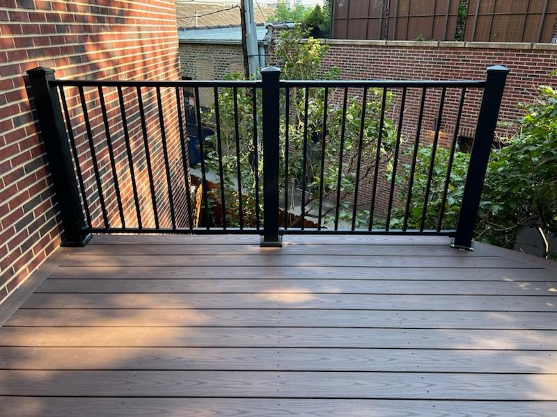 Composite decking with black railing overlooking a garden with lush greenery.-porch guard rails