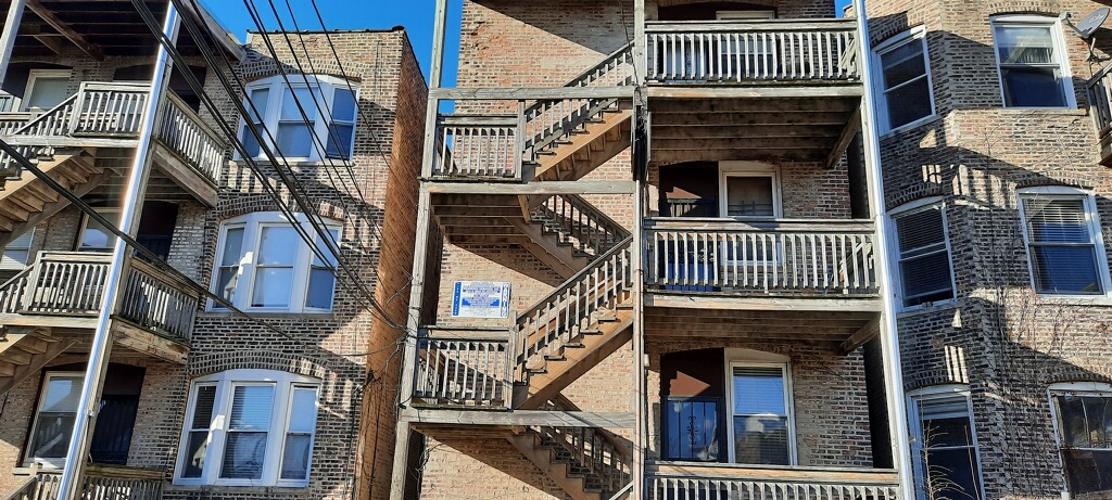 multiporches building with exterior wooden staircases and balconies under a clear blue sky.