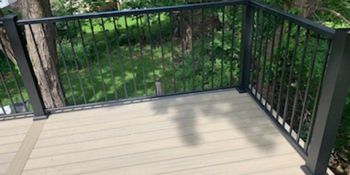 A well-constructed deck featuring railing kits for deck, with sturdy metal balusters and handrails, framing a serene, tree-filled backyard.