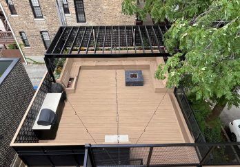 Rooftop deck Overhead view of a rooftop deck with beige flooring, black railing, surrounded by trees and buildings